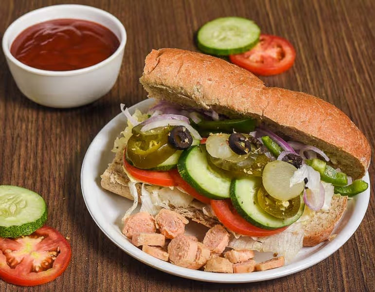 sandwich with various toppings on a plate with a side of ketchup.